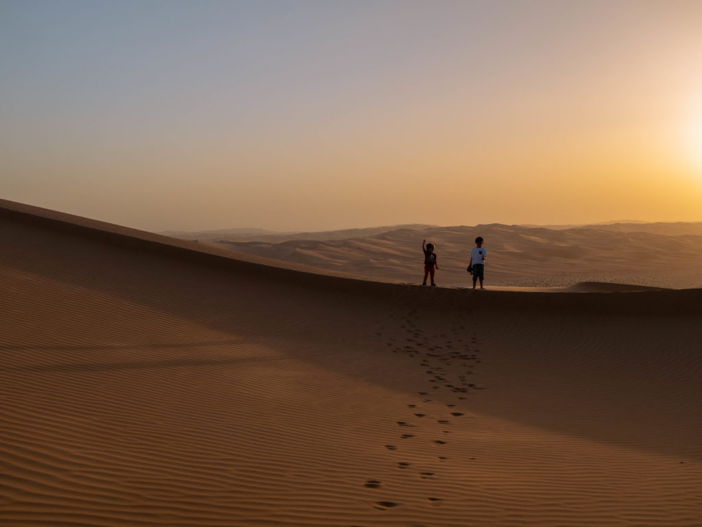 2 enfants sur la crète de la dune devant le coucher de soleil